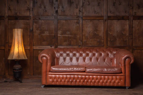 Classic brown loft style interior with wood paneling, chesterfield sofa. Old sofa on the background of vintage wall. High quality photo — Stock Photo, Image