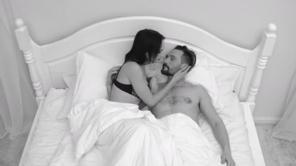 Young woman in her underwear lies in bed with a naked man. Couple in love in bed. Black and white shooting. High quality — Stock Video