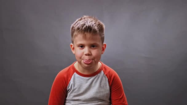 Jongen toont zijn tong op camera in de studio. Kind steekt zijn tong uit. Hoge kwaliteit — Stockvideo