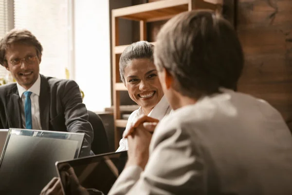 Gente divertida de negocios. El personal feliz de la oficina se sonríe durante la reunión de negocios mientras trabaja en la mesa de la oficina con computadoras portátiles en ella. Foto de alta calidad — Foto de Stock