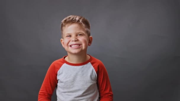 Το αγόρι χαμογελάει ευρέως στο στούντιο σε ένα απομονωμένο φόντο. Ένα παιδί χαμογελάει στο στούντιο. Υψηλή ποιότητα — Αρχείο Βίντεο