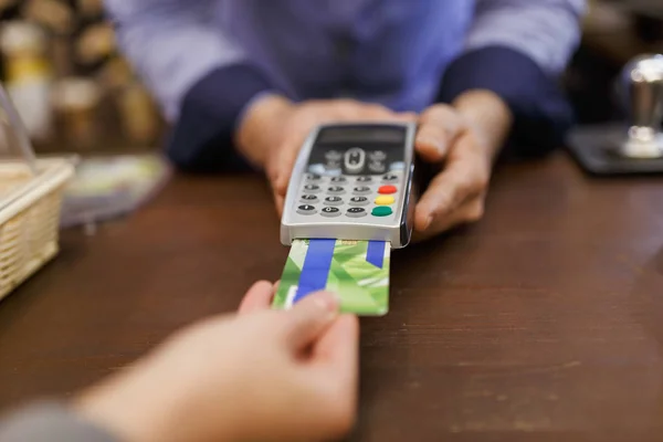 Foto do comprador com cartão bancário e vendedor com terminal na mão — Fotografia de Stock