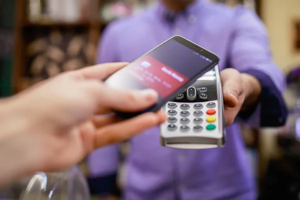 Imaginea cumpărătorului plătește cu smartphone-ul lângă vânzător cu terminal — Fotografie, imagine de stoc