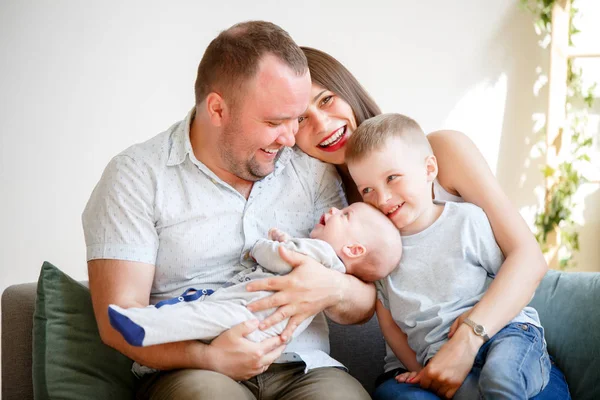 Foto de pais felizes com dois filhos no sofá no apartamento — Fotografia de Stock