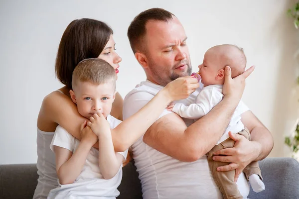 Foto de padres jóvenes felices con dos hijos sentados en el sofá — Foto de Stock