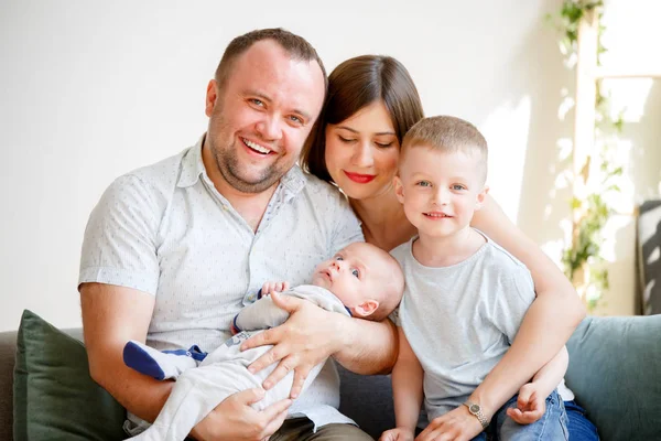 Retrato de padres sonrientes con dos hijos pequeños sentados en un sofá — Foto de Stock