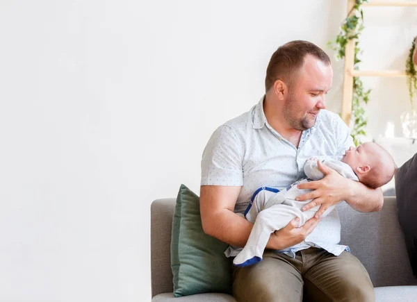 Zdjęcie młodych ojca z nowo narodzonego syna, siedząc na kanapie — Zdjęcie stockowe