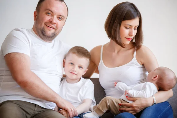 Image of happy married couple with two young sons sitting on sofa — Stock Photo, Image