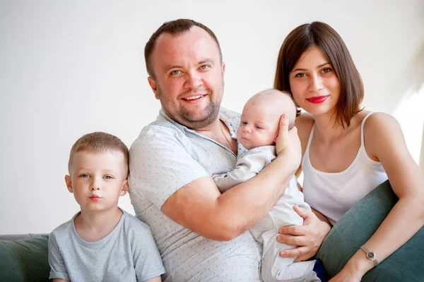 Foto de casal com dois filhos jovens sentados no sofá — Fotografia de Stock