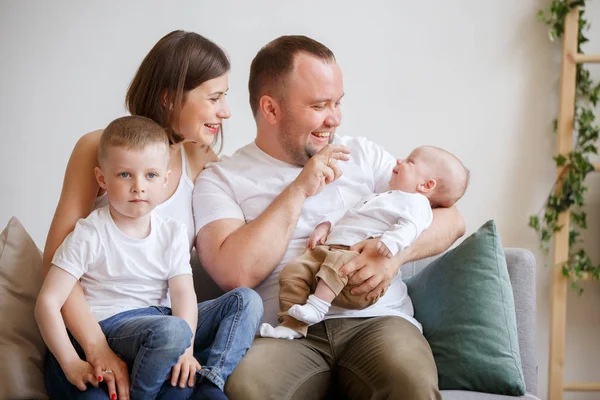 Retrato de padres sonrientes con dos hijos pequeños sentados en un sofá — Foto de Stock