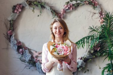 Buket elinde ile gülümseyen çiçekçi portresi