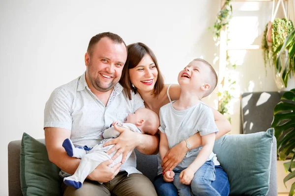 Imagem de pais sorridentes com dois filhos jovens sentados no sofá — Fotografia de Stock