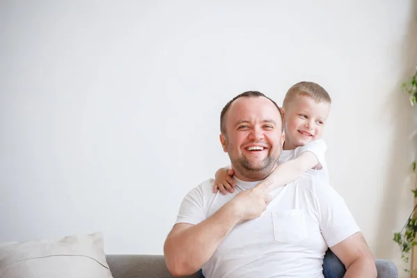 Foto des jungen Vaters mit seinem Sohn vor leerem Hintergrund — Stockfoto