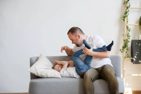 年轻父亲与儿子在沙发上玩耍的形象 — 图库照片