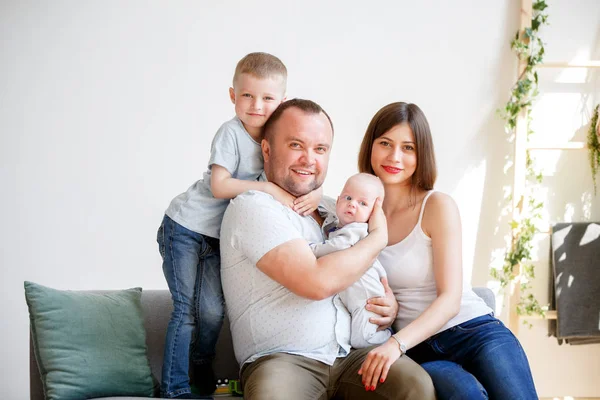 Imagem de casal com dois filhos jovens sentados no sofá — Fotografia de Stock