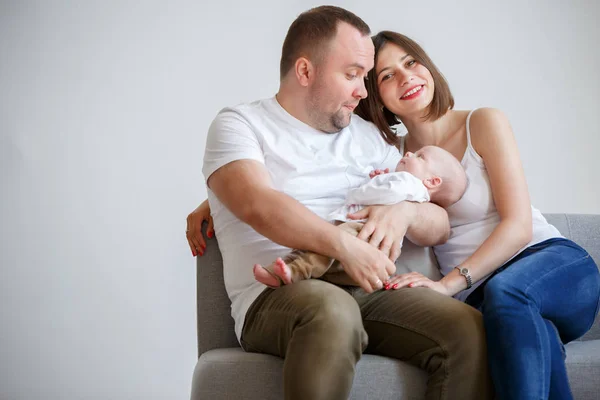 Mutlu evli çift kanepede oturan yeni doğan bebekle fotoğrafı — Stok fotoğraf