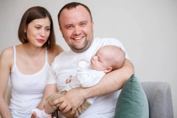 Foto de casal feliz com criança sentada no sofá — Fotografia de Stock