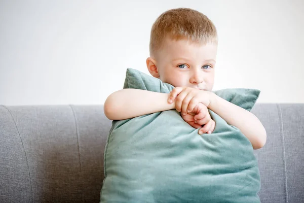 Bild av pojke med kudden som sitter på soffan — Stockfoto