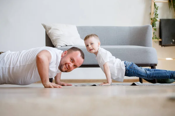Foto de papá feliz y su hijo empujando en el suelo — Foto de Stock