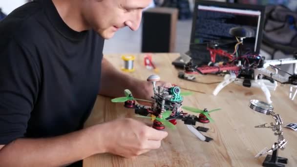 Человек чинит разбившийся дрон. Лаборатория обслуживания квадрокоптеров. 4K — стоковое видео