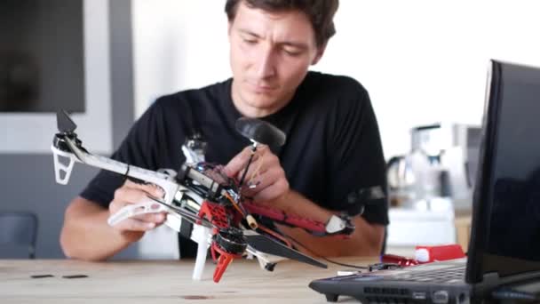 Человек чинит разбившийся дрон. Лаборатория обслуживания квадрокоптеров. 4K — стоковое видео