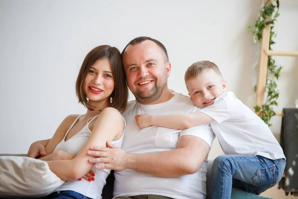 Photo of cuddling parents with son sitting on sofa — Stock Photo, Image