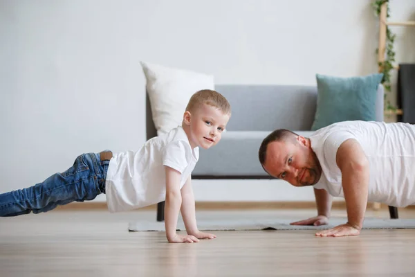 Bild vom glücklichen Vater und Sohn, die sich auf den Boden schieben — Stockfoto