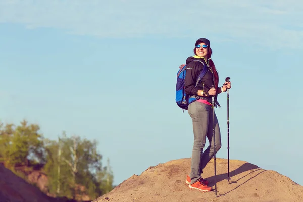 Bild einer Touristin mit Wanderstöcken und Rucksack auf einem Hügel — Stockfoto