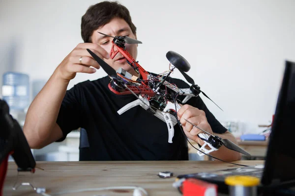 Image of man fixing square copter at table — Stock Photo, Image