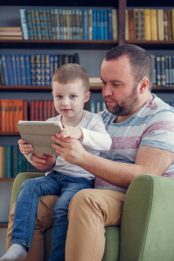 Baba ve küçük oğlu ile tablet yeşil sandalye üzerinde oturan fotoğrafı
