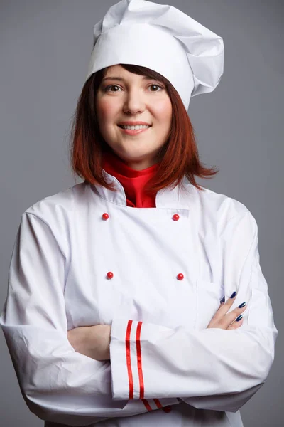 Φωτογραφία της γυναίκα μάγειρας σε λευκό χιτώνα και καπάκι με τα χέρια σταυρωμένα στη μέση — Φωτογραφία Αρχείου