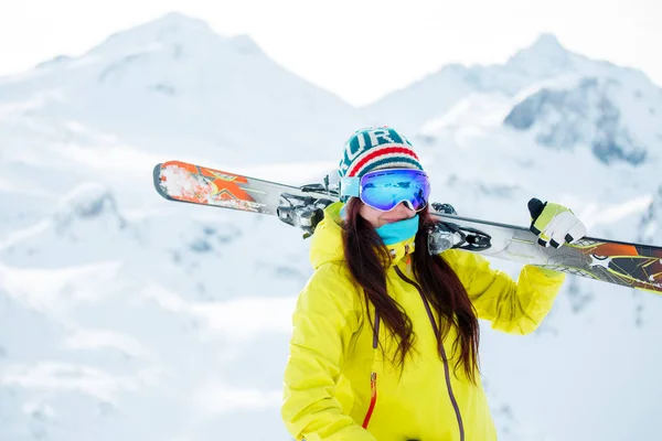 Imagem de mulher desportiva com esquis no ombro contra o fundo da colina nevada — Fotografia de Stock