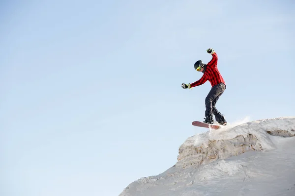 Imagen del hombre con snowboard saltando desde la ladera nevada de la montaña —  Fotos de Stock