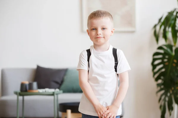 Obrázek chlapce v bílé tričko s batohem na pozadí pohovka — Stock fotografie