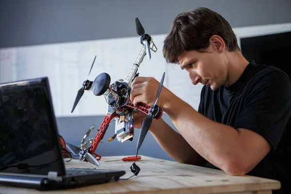 Photo of young engineer mending squatter sitting at table with laptop — Stock Photo, Image