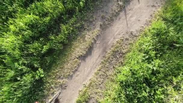 Вид зверху вниз над стежкою сільської дороги з велосипедистом — стокове відео