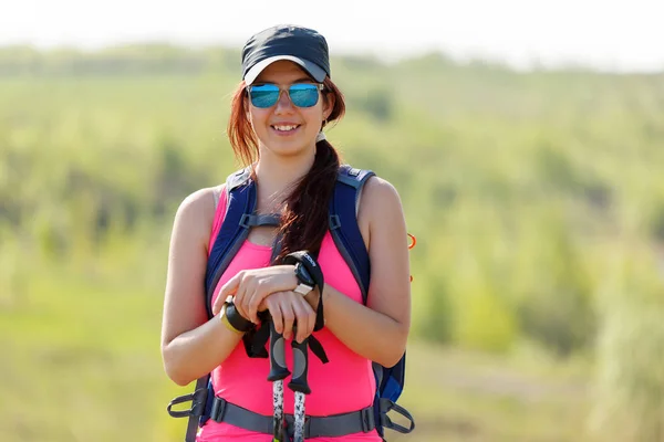 Immagine di atleta donna sorridente con bastoni e zaino con sfondo sfocato — Foto Stock