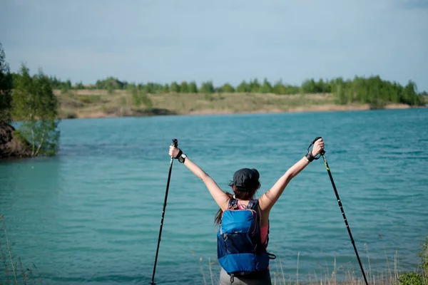 照片从女性游客的背部与步行棍在湖背景上的夏季天提出的武器 — 图库照片