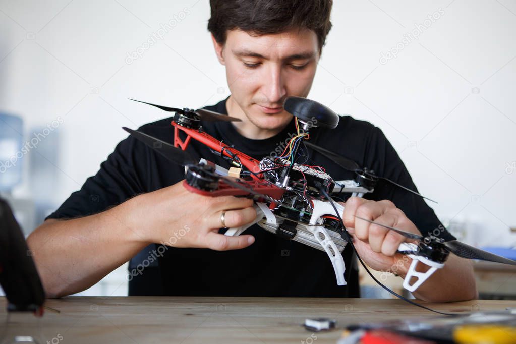 Image of engineer mending square copter at table