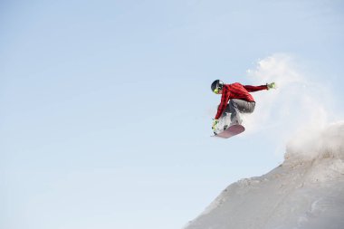 Karlı dağ yamacı atlama snowboard ile kask içinde adam görüntüsünü