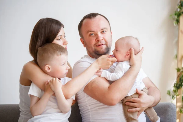 Imagen de padres jóvenes y felices con dos hijos sentados en el sofá — Foto de Stock