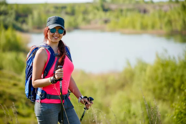 Foto di giovane ragazza atletica con bastoni da passeggio sullo sfondo del lago e vegetazione verde — Foto Stock