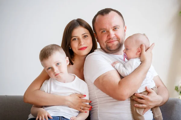 Immagine di giovani genitori felici con due figli seduti sul divano — Foto Stock