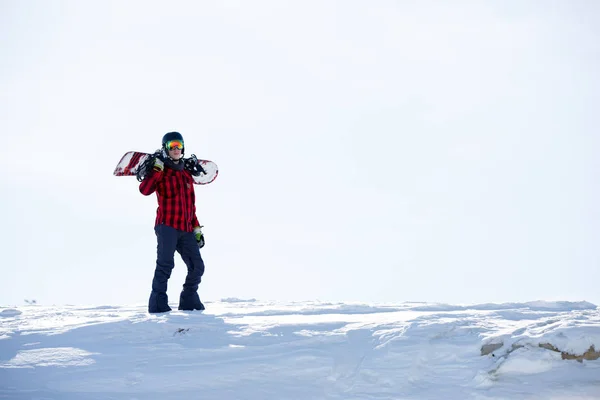 Image of man with snowboard on shoulders standing on snowy mountainside — Stock Photo, Image