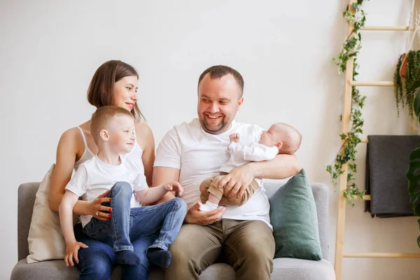 Foto de padres sonrientes con dos hijos pequeños sentados en el sofá — Foto de Stock