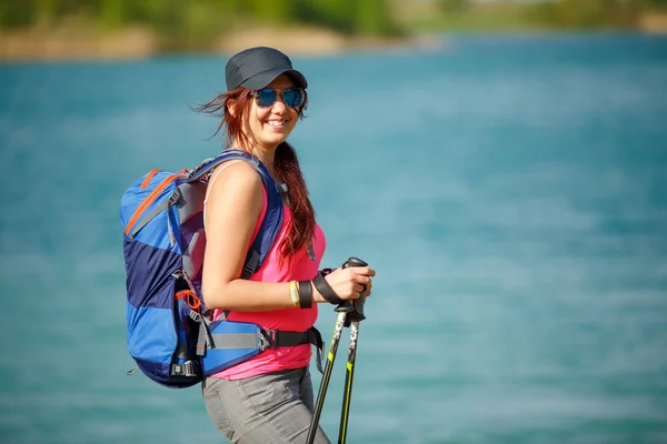 Portrait of smiling female athlete with walking sticks on blurred background — Stock Photo, Image