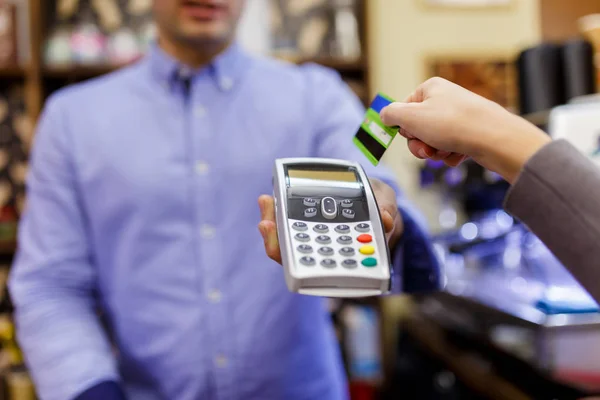 Foto del vendedor con terminal en las manos y comprador con tarjeta bancaria . — Foto de Stock