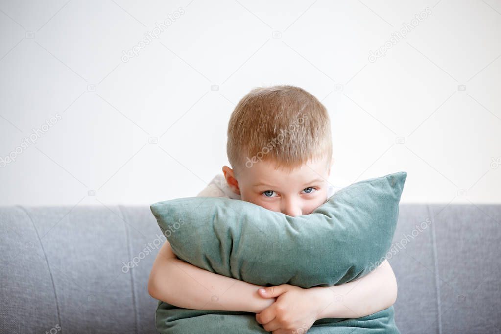 Photo of boy with pillow sitting on couch