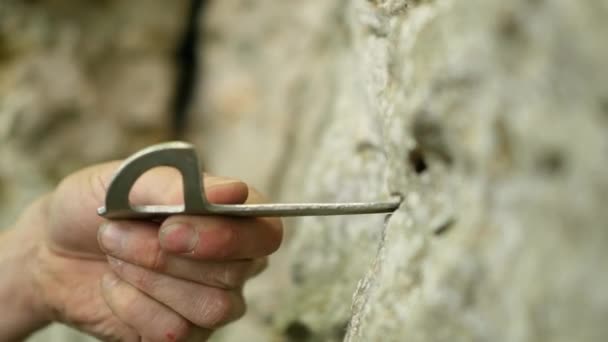 Colocación de pitón hoja con martillo en la grieta de piedra caliza — Vídeo de stock