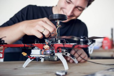 Image of young man cleaning quadrocopter at table clipart